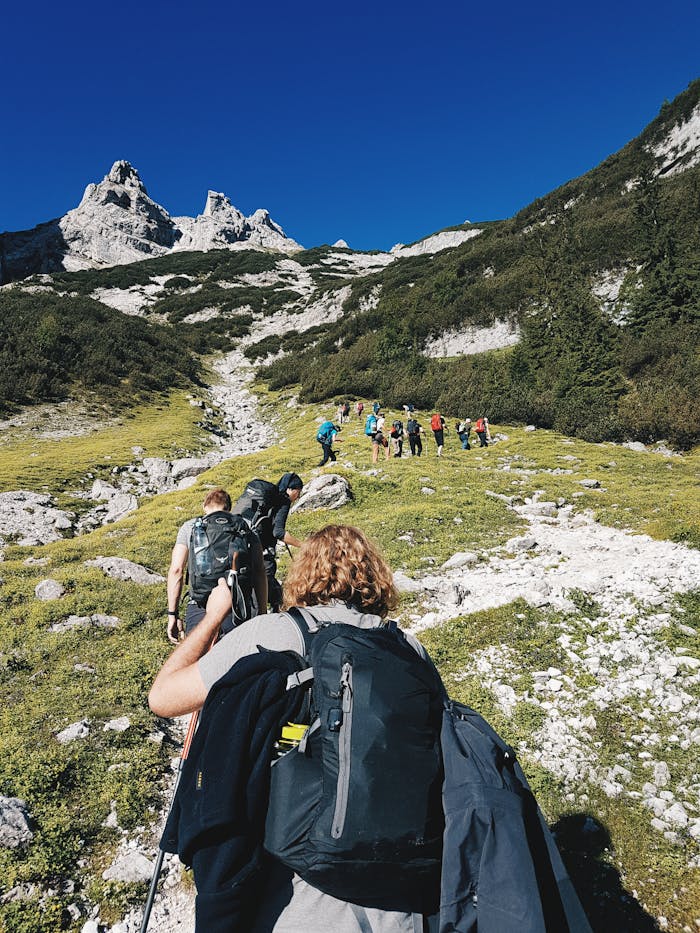 contact-img A group of hikers trekking through the rugged landscape of Garmisch-Partenkirchen, Germany under a clear blue sky.