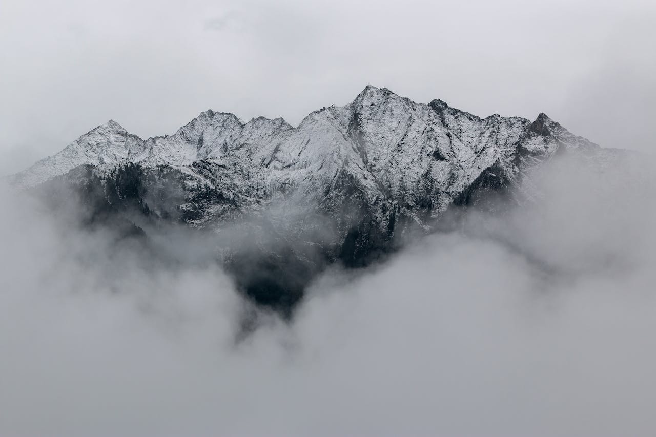 Mastering the First Impression: Your intriguing post title goes here A breathtaking view of snow-covered mountain peaks surrounded by dense fog, creating a mystical landscape.